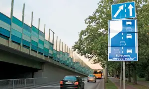 Znak drogowy informuje o zalecanej zasadzie ruchu, czyli jeździe na suwak. Samochody jadą pod ekranami akustycznymi.