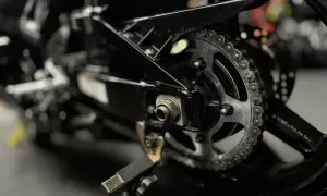 Zbliżenie na czysty łańcuch i zębatkę motocykla na stojaku.