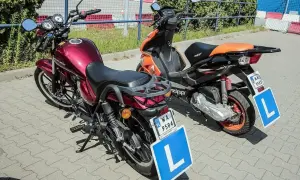 Dwa skutery z literą "L" na tablicach, gotowe do nauki jazdy. Zastanawiasz się, ile kosztują prawo jazdy AM?