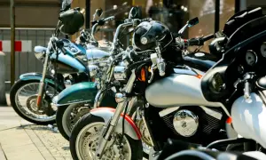 Kilka motocykli zaparkowanych na chodniku, w tym niebieski, zielony i srebrny.