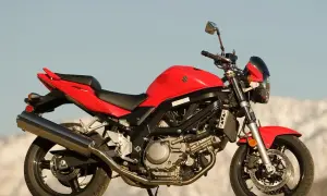 Czerwony motocykl Suzuki SV 650 na tle nieba i gór.