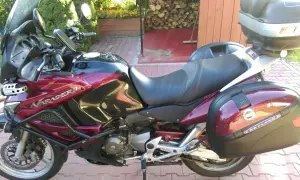 Czerwony motocykl Honda Varadero 1000 z kuframi, zaparkowany na podjeździe.