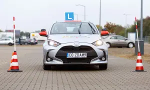 Srebrny samochód nauki jazdy z literą "L" na dachu i pachołkami po bokach. Czas na praktykę po teorii? To auto czeka!