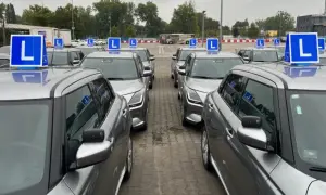 Rząd srebrnych samochodów nauki jazdy z niebieskimi tabliczkami "L" na dachach. Zastanawiasz się, ile razy dziennie można zdawać egzamin teoretyczny na prawo jazdy?