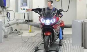 Mężczyzna w słuchawkach obsługuje motocykl na hamowni.