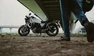 Biały motocykl pod mostem, obok idzie mężczyzna z kaskiem. Zastanawiasz się, jakie prawo jazdy na motor 1000?