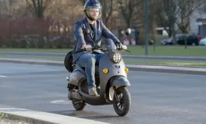 Mężczyzna w kasku jedzie na skuterze. Dowiedz się, od ilu lat można mieć kartę motorowerową, by legalnie poruszać się po drogach.