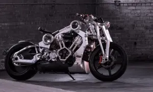 Wyjątkowy, lśniący motocykl, prawdopodobnie najdroższy motor na świecie, z masywnym silnikiem i detalami z polerowanego metalu, na tle ceglanej ściany.