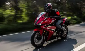 Motocyklista w kasku pędzi czerwonym sportowym motocyklem. Zastanawiasz się, jakie prawo jazdy na motor jest potrzebne, by poczuć tę wolność?