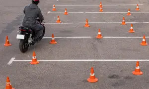 Motocyklista na placu manewrowym, otoczony pomarańczowymi stożkami. Ile jest egzaminów na prawo jazdy? Tyle, ile torów do pokonania!