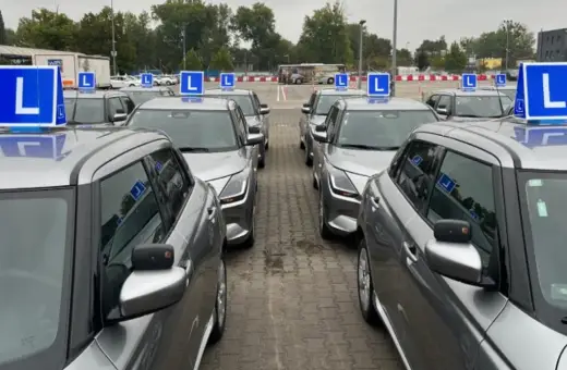 Rząd srebrnych samochodów nauki jazdy z niebieskimi tabliczkami "L" na dachach. Zastanawiasz się, ile razy dziennie można zdawać egzamin teoretyczny na prawo jazdy?