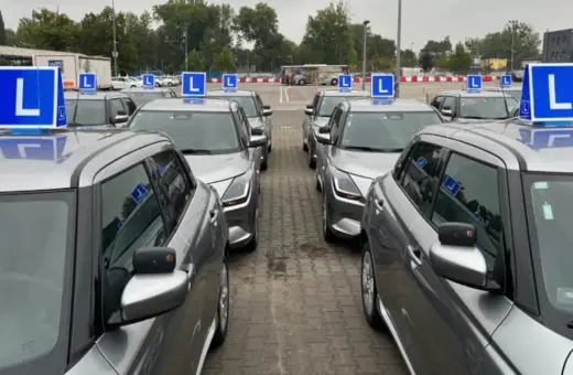 Rząd srebrnych samochodów nauki jazdy z niebieskimi tabliczkami "L" na dachach. Zastanawiasz się, ile razy dziennie można zdawać egzamin teoretyczny na prawo jazdy?