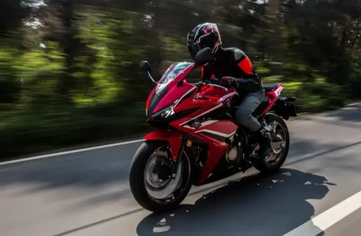 Motocyklista w kasku pędzi czerwonym sportowym motocyklem. Zastanawiasz się, jakie prawo jazdy na motor jest potrzebne, by poczuć tę wolność?