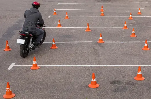 Motocyklista na placu manewrowym, otoczony pomarańczowymi stożkami. Ile jest egzaminów na prawo jazdy? Tyle, ile torów do pokonania!