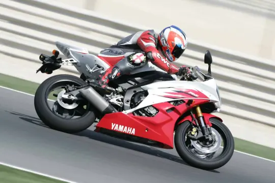 Motocyklista w czerwonym kombinezonie śmiga na torze Yamahą R6. Od ilu lat można robić prawo jazdy na motor 600? Od 20.