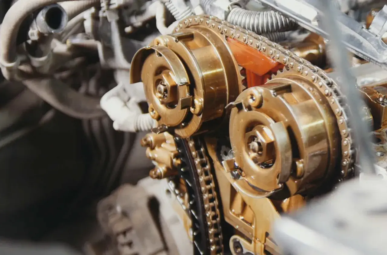 Mechanizm rozrządu DOHC z widocznym łańcuchem, a nie paskiem. Złote koła zębate i metalowy łańcuch.