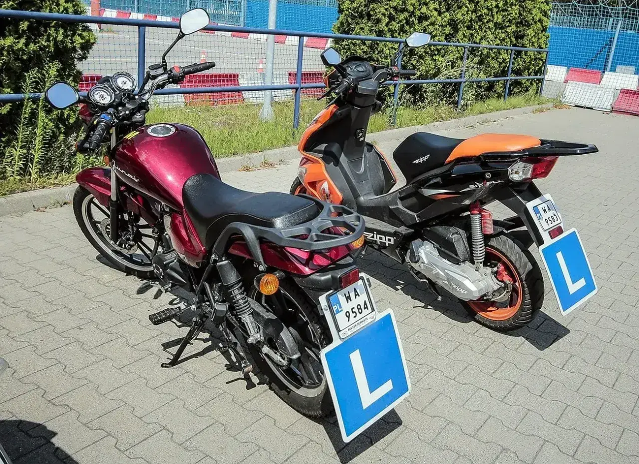 Dwa skutery z literą "L" na tablicach, gotowe do nauki jazdy. Zastanawiasz się, ile kosztują prawo jazdy AM?