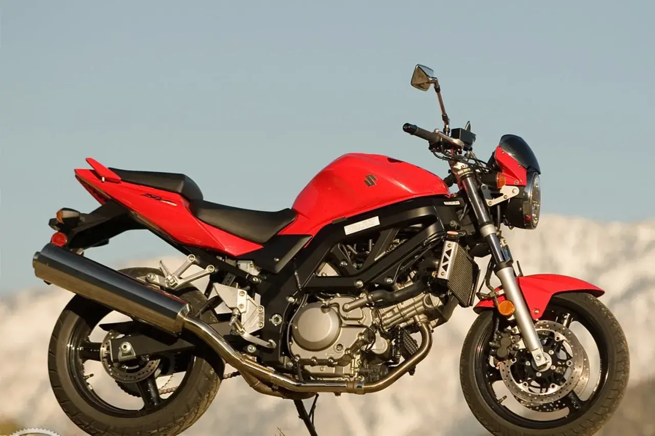 Czerwony motocykl Suzuki SV 650 na tle nieba i gór.