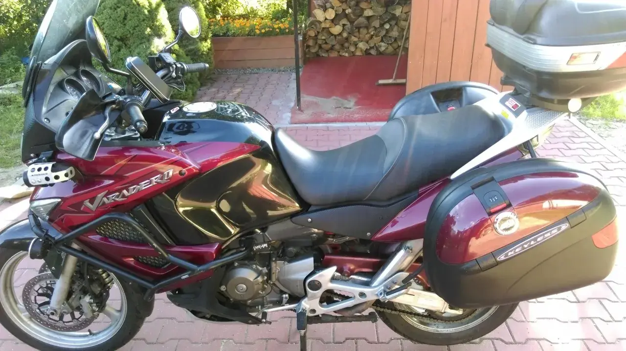 Czerwony motocykl Honda Varadero 1000 z kuframi, zaparkowany na podjeździe.