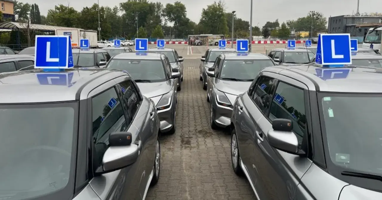 Rząd srebrnych samochodów nauki jazdy z niebieskimi tabliczkami "L" na dachach. Zastanawiasz się, ile razy dziennie można zdawać egzamin teoretyczny na prawo jazdy?