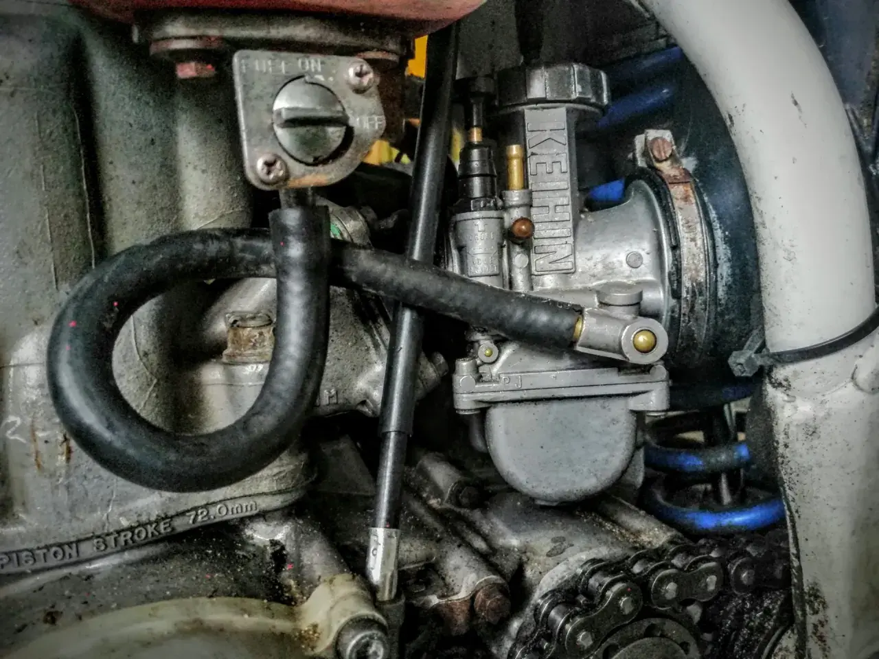 Zbliżenie na gaźnik motocyklowy marki Keihin, przewody paliwowe i fragment silnika.