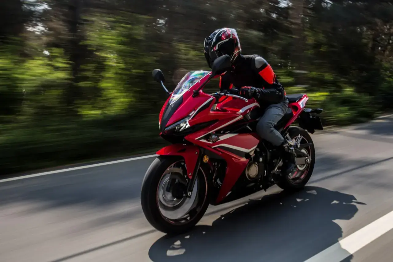 Motocyklista w kasku pędzi czerwonym sportowym motocyklem. Zastanawiasz się, jakie prawo jazdy na motor jest potrzebne, by poczuć tę wolność?