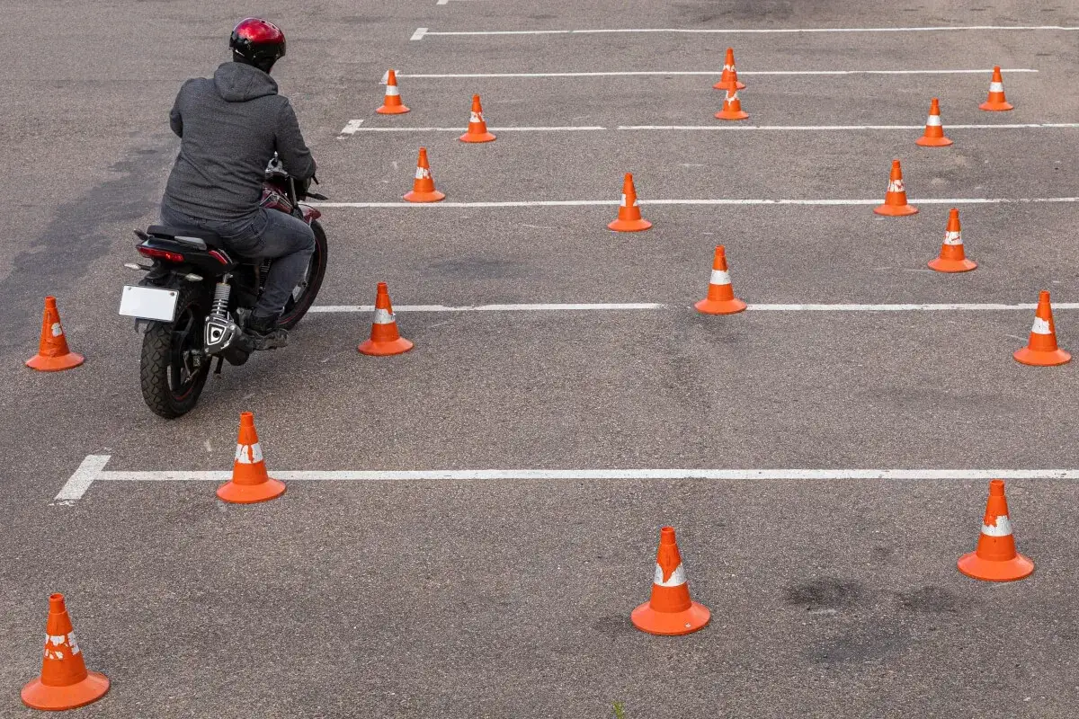 Motocyklista na placu manewrowym, otoczony przez pomarańczowe pachołki. Ile jest egzaminów na prawo jazdy? Tyle, ile pachołków na torze!
